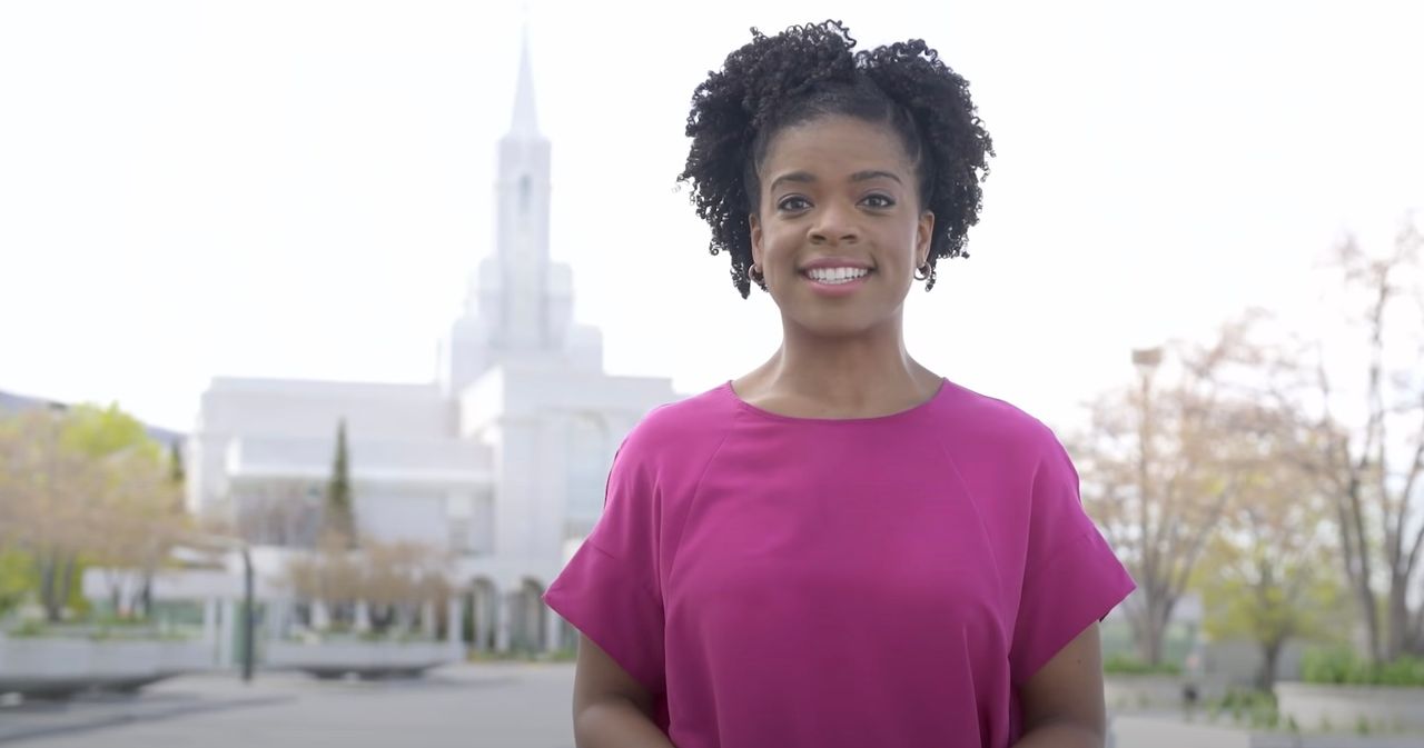 Wiosną kobieta stoi przed świątynią i wyjaśnia cel chrztów za zmarłych